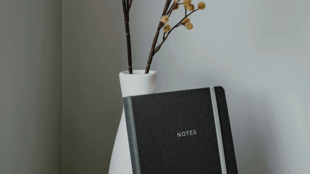 Black notebook in white vase on a desk – symbolizing organized customer support and administration services.