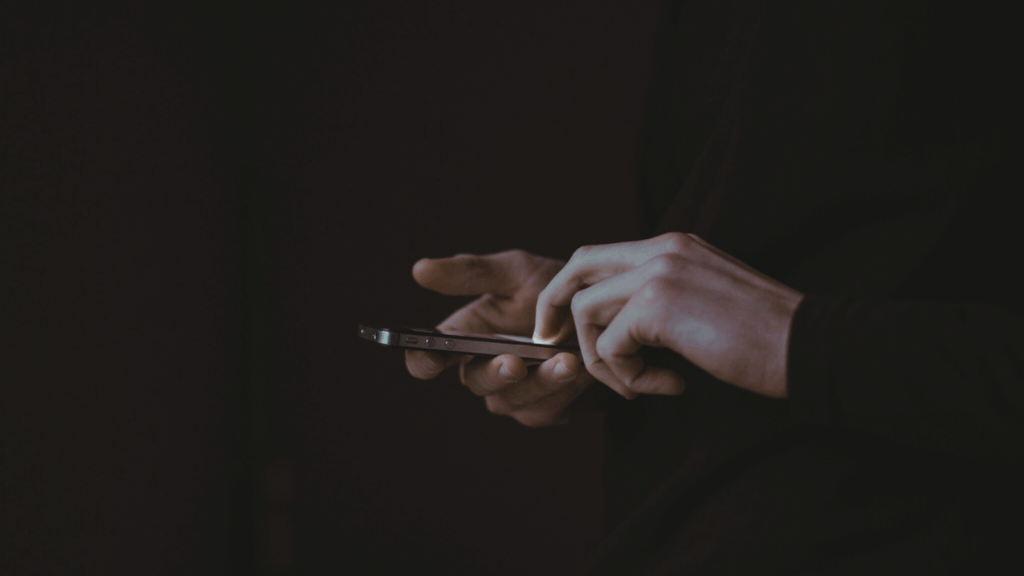 Hands using a smartphone to manage social media accounts